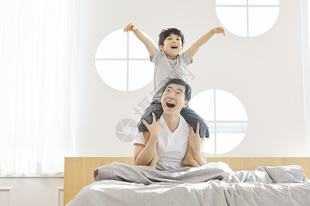 卧室里坐在父亲肩膀上开心的小男孩图片