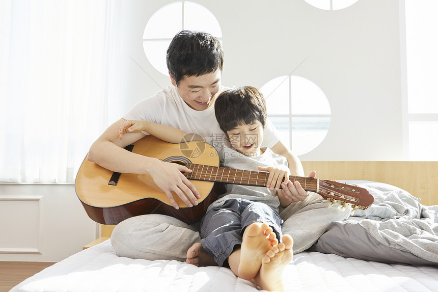 床上拿着吉他开心的父子图片