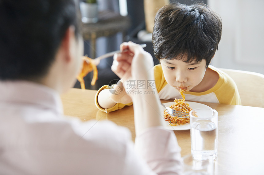 父子二人在餐桌上吃意面图片