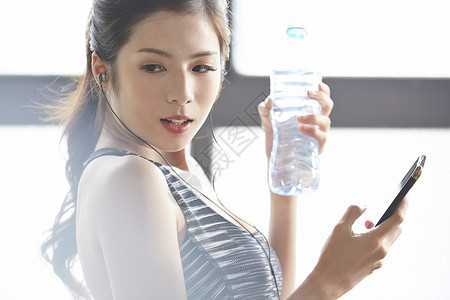拿着水瓶和手机的年轻女子图片