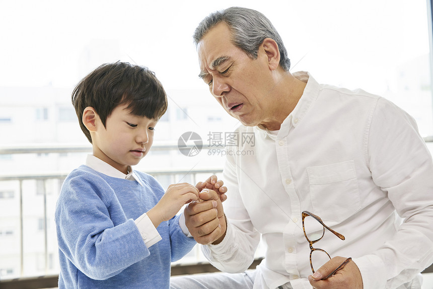 爷爷观察小男孩手上的伤口图片