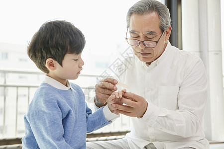 爷爷担心的看着小男孩受伤的手指图片