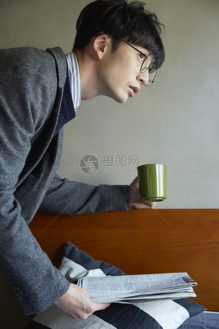 拿着报纸喝咖啡的青年男性图片