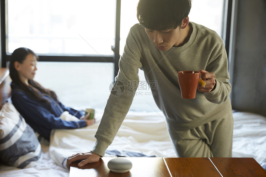 居家卧室拿着水杯的青年男子图片