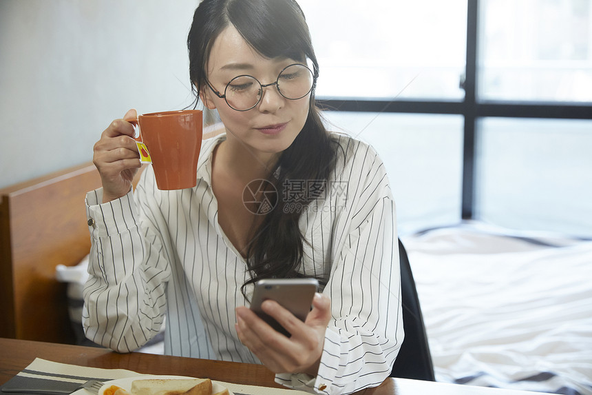 青年女子拿着水杯看手机图片