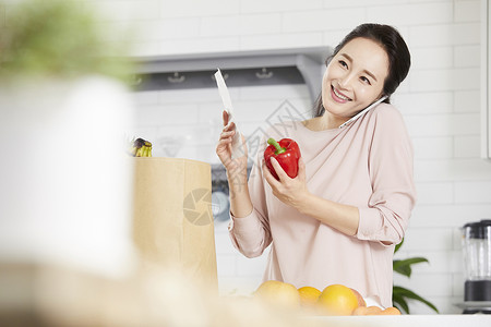 手上拿着水果接听电话的成年女子图片