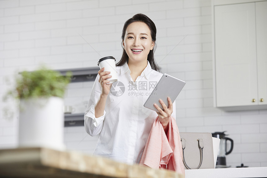 拿着咖啡和平板微笑的青年女子图片