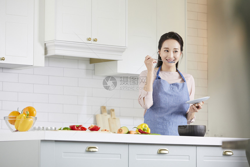 拿着勺子品尝料理的女青年图片