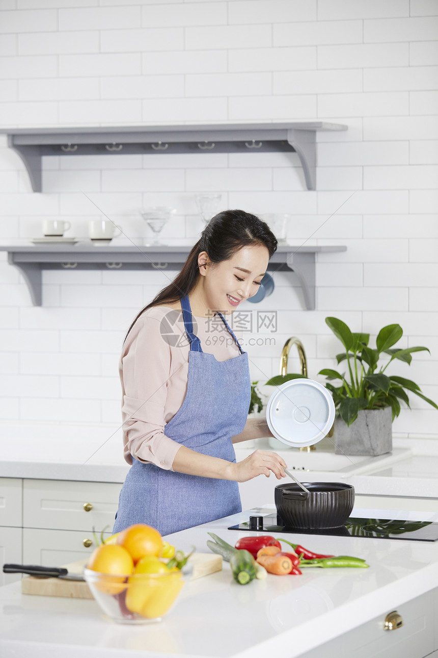 厨房里烹饪食物的女青年图片