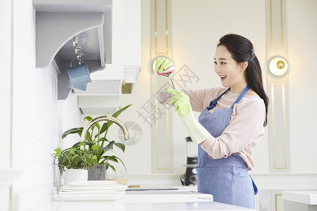 戴着橡胶手套洗碗微笑的成年女子图片