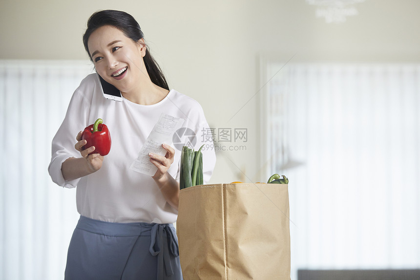 拿着甜椒打电话的青年女性图片