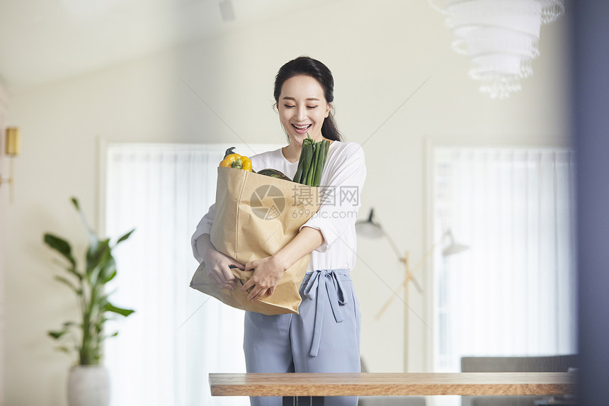 抱着一袋蔬果微笑的年轻女子图片