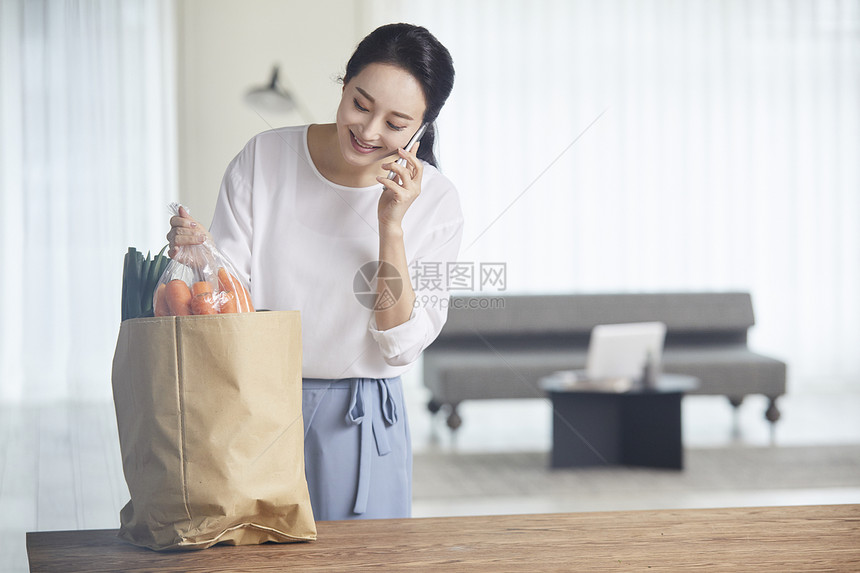 拿着蔬菜打电话的青年女性图片