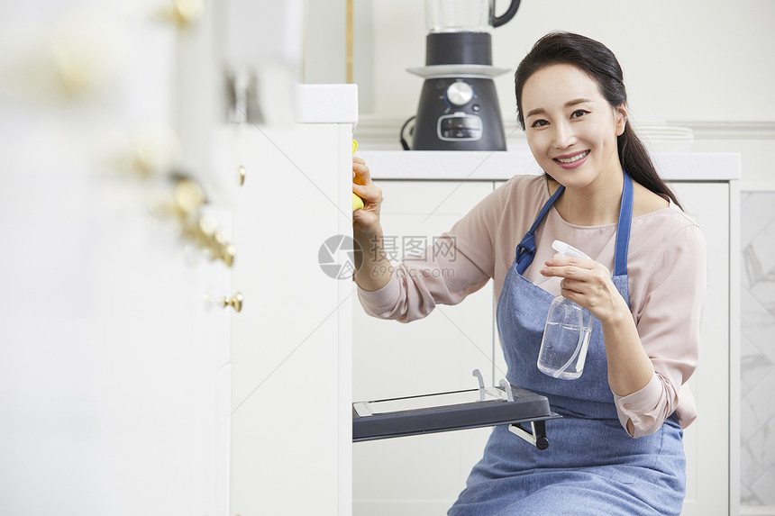 清洁使用喷雾微笑的年轻女子图片