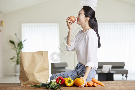 年轻女子微笑的闻苹果的气味图片