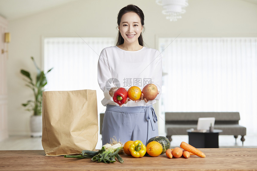 年轻女子双手拿着蔬果微笑图片