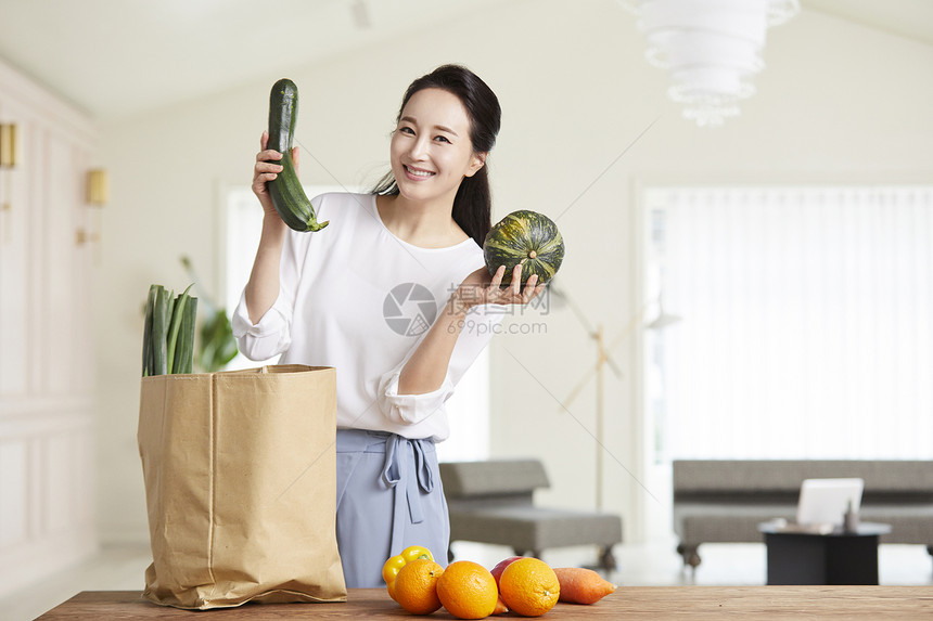 举起蔬菜微笑的成年女子图片