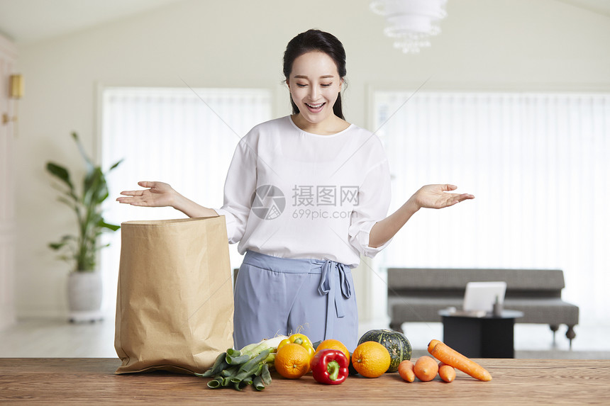 年轻女子看着摆放的水果低头微笑图片