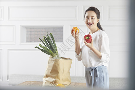 厨房里拿着蔬果开心的年轻女子图片