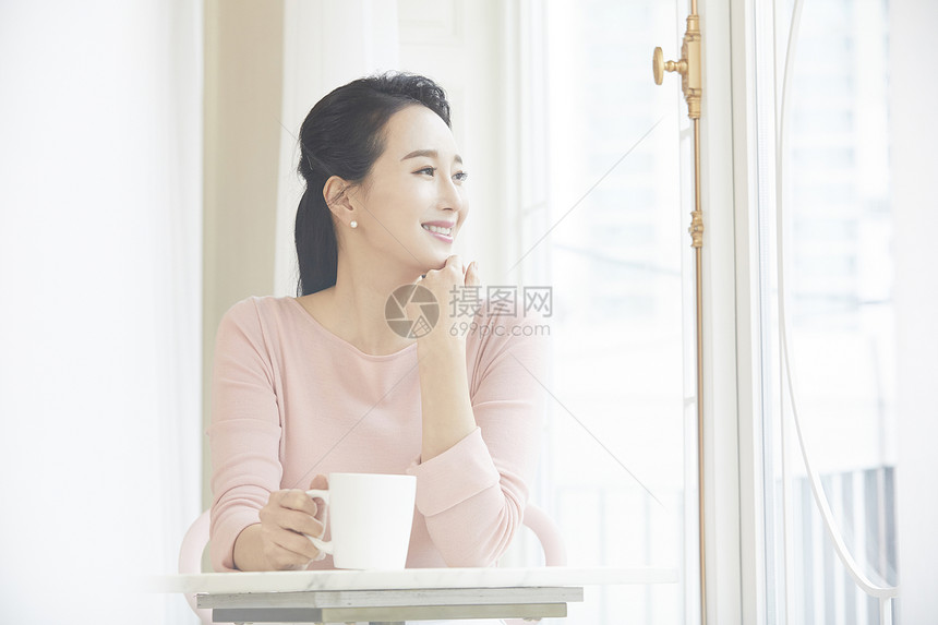 青年女子拿着咖啡看窗外图片