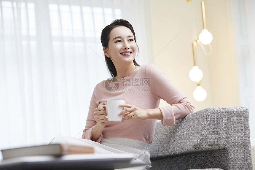 沙发上拿着咖啡微笑的气质女性图片