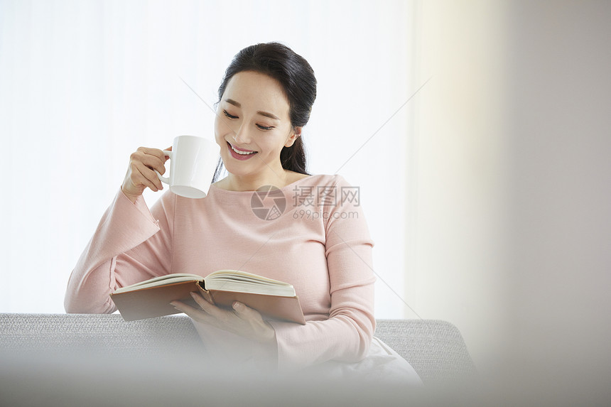 拿着咖啡阅读书籍的成年女子图片
