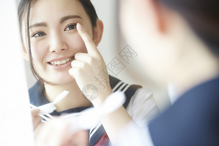 夏装焕新高中女孩照着镜子佩戴美瞳背景