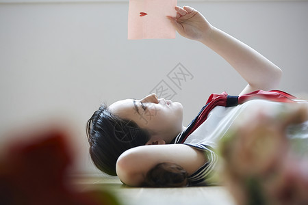 躺在地上看着情书的年轻女子图片