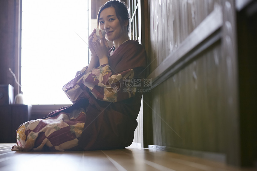 坐在地上喝茶的青年女性图片