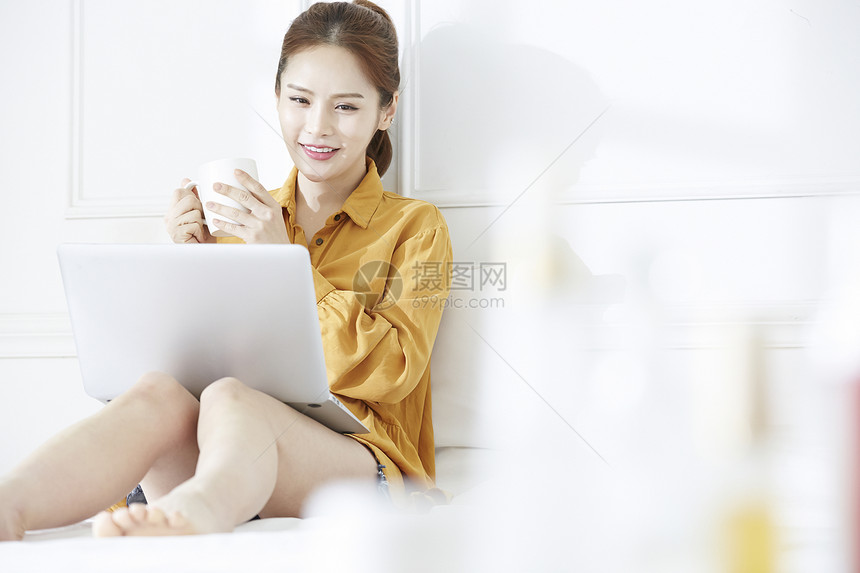 拿着咖啡看电脑的女青年图片