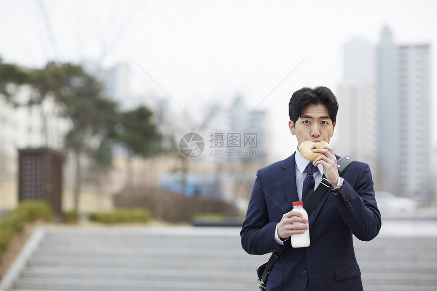 早晨路上吃着面包的成年男子图片