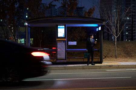 夜晚公交站台等车的青年男性图片