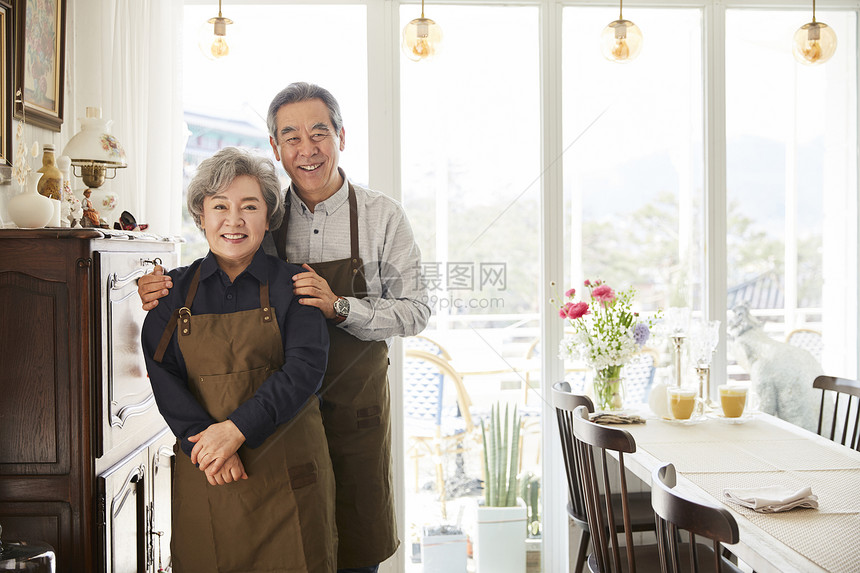 老夫妇戴围裙在室内一起休闲生活图片