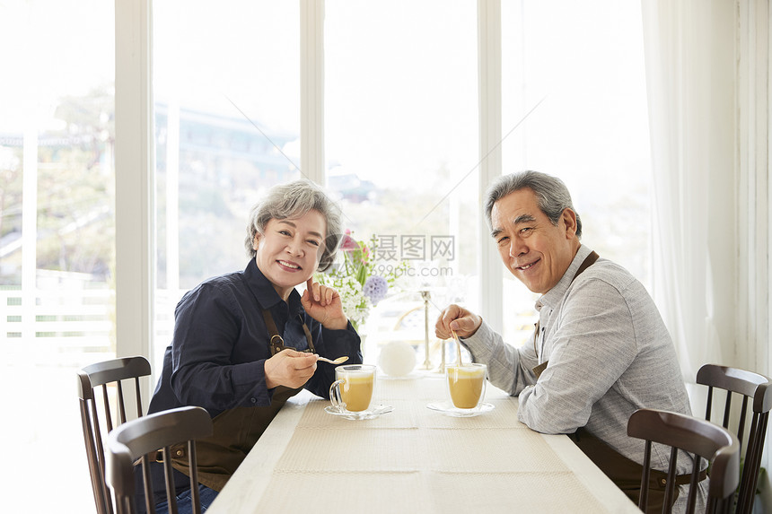 老夫妇戴围裙在室内一起休闲喝咖啡图片