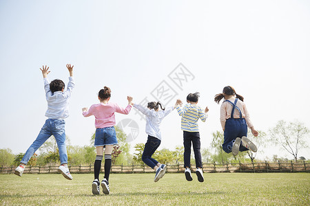 草坪上跳跃的孩子们背影高清图片