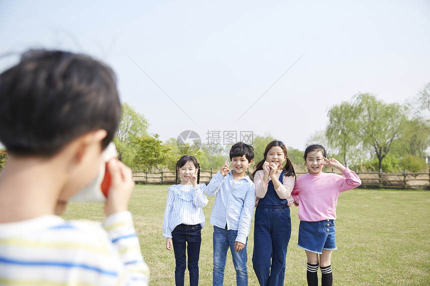 男孩在公园给朋友们拍照图片