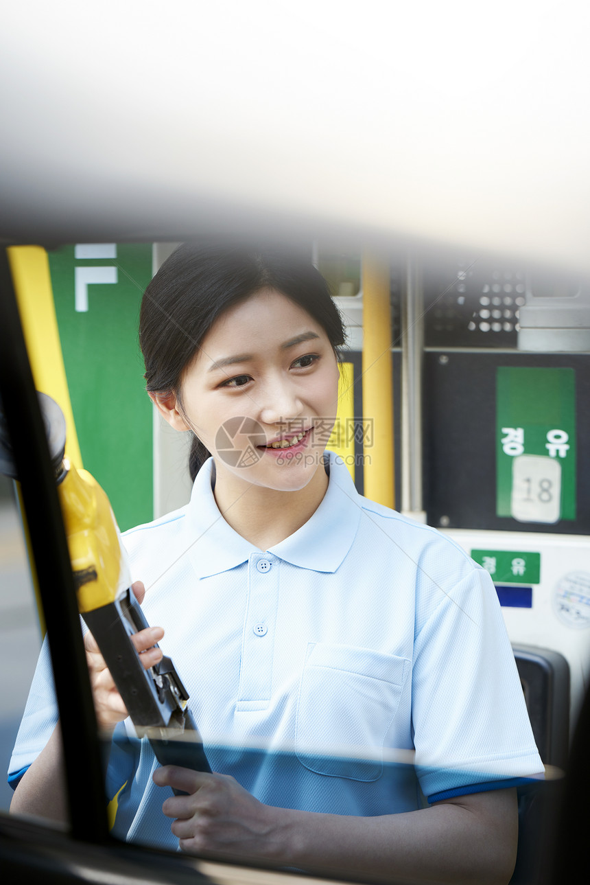 汽车加油站拿着加油枪的年轻女子图片