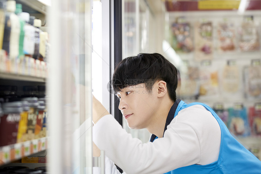 便利店整理冰柜的成年男子图片
