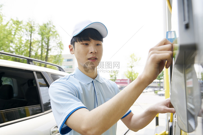 男子在加油站兼职给汽车加油图片