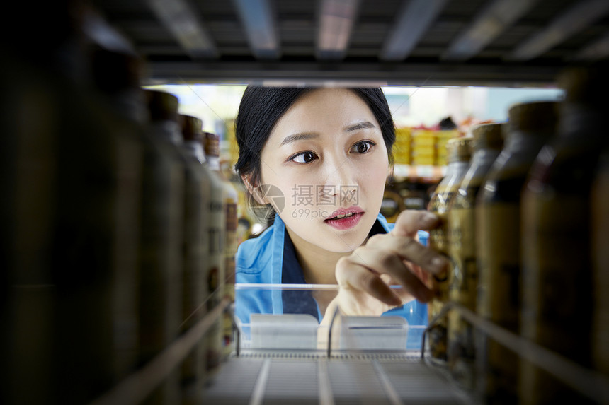 便利店女职员在整理货架商品图片