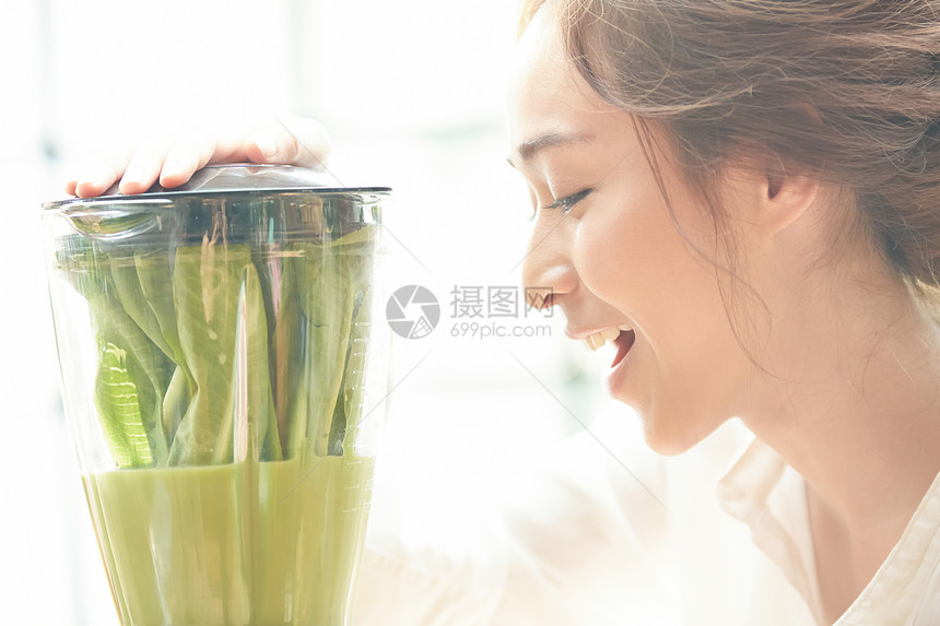 榨蔬菜汁开心的年轻女子图片