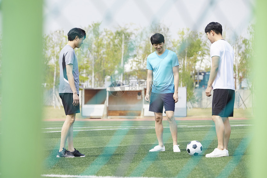 三个青少年在操场上提足球图片