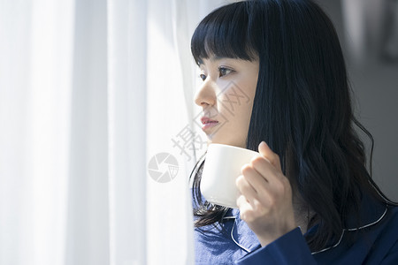 窗边拿着咖啡的女青年图片