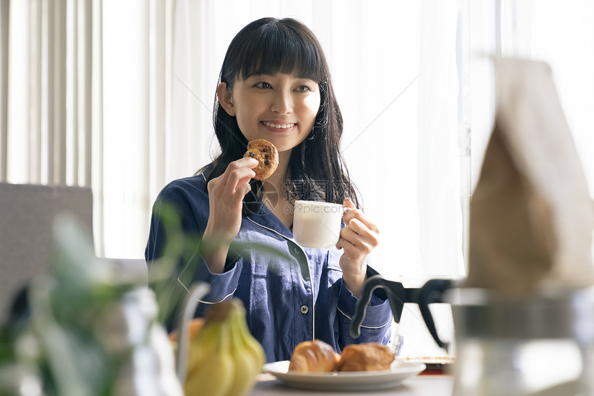 拿着咖啡和饼干的年轻女子图片