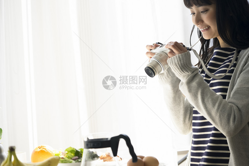 年轻女子微笑的拍摄食物照片图片