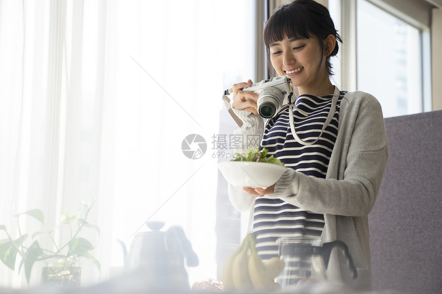 年轻女子微笑的拿着相机拍照图片