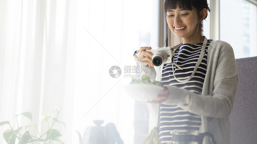 拿着相机拍照开心的年轻女子图片