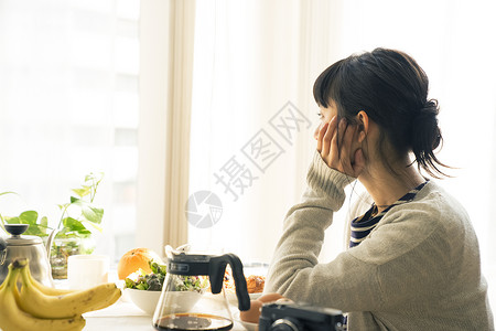 年轻女子捧着脸看向窗外图片