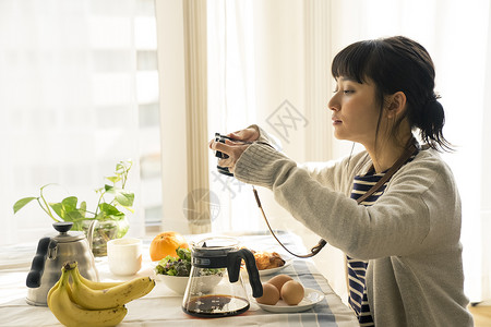 餐厅里拿着相机拍照的年轻女子图片