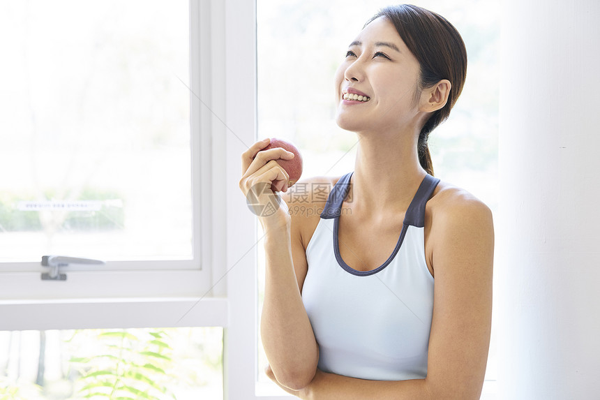 穿运动装手拿苹果的健康女性图片